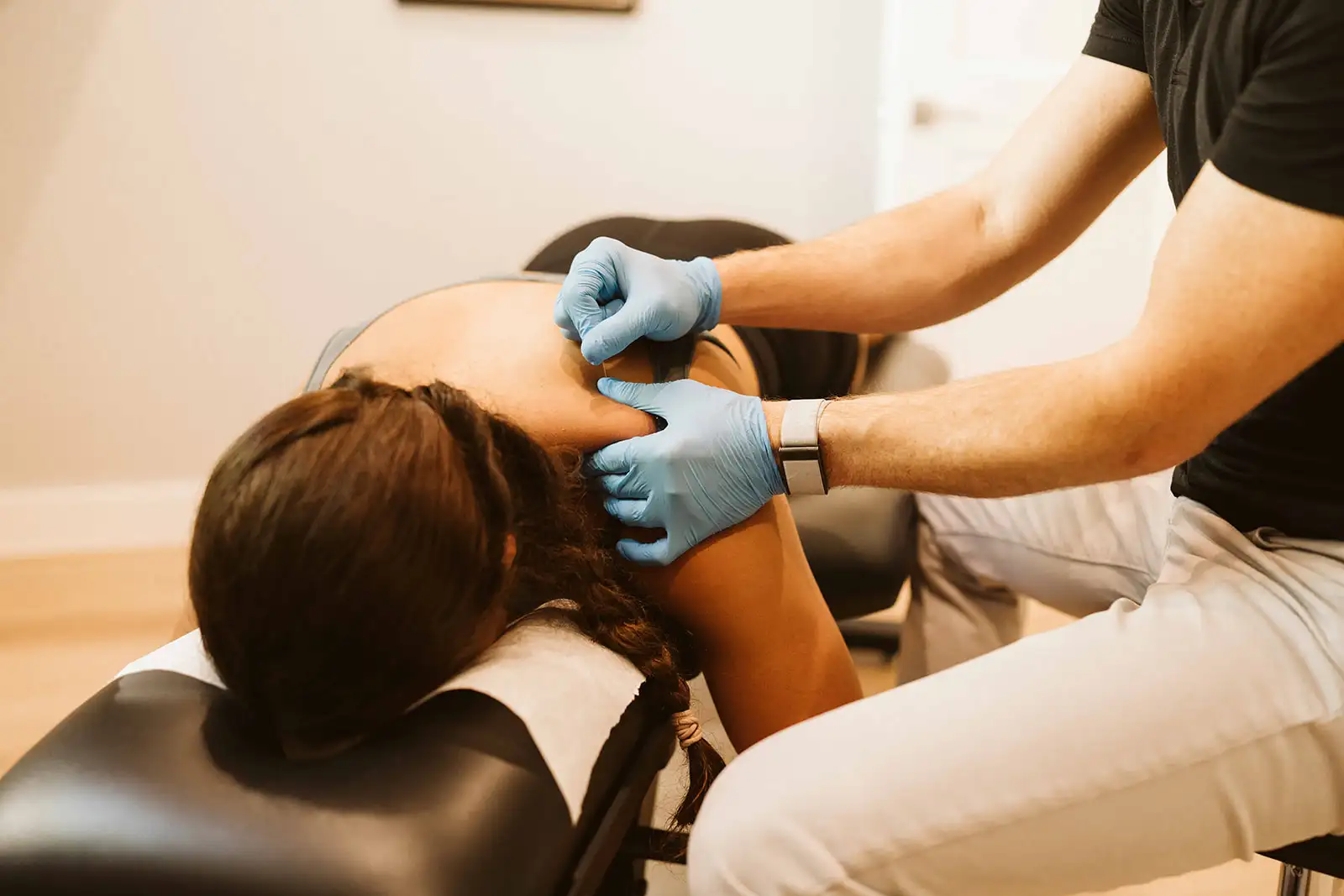Close-up of dry needling treatment near a patient's shoulder