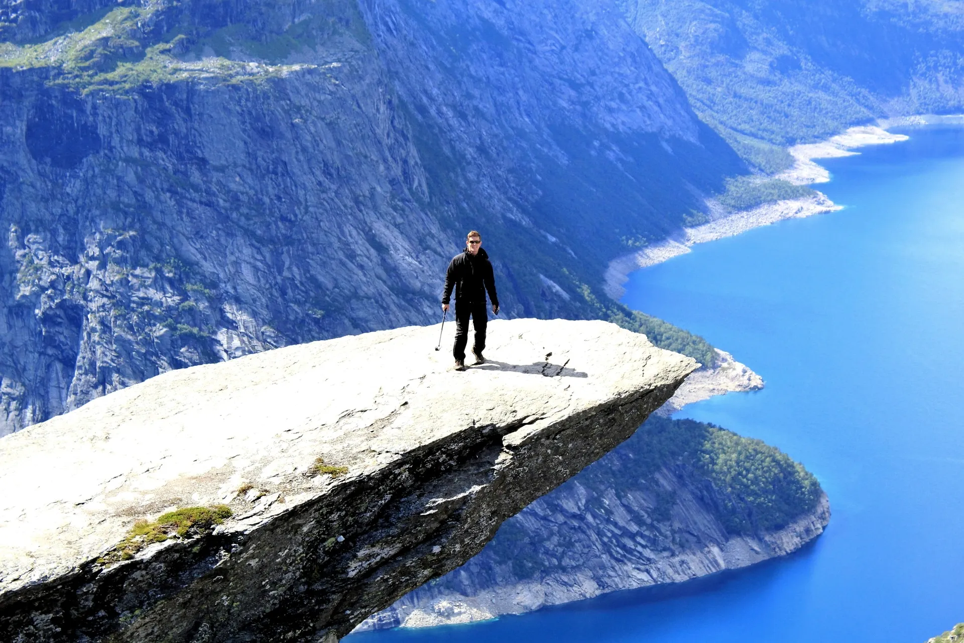 Dr. Spencer Hiebert standing on an alpine rock overlook above a blue lake
