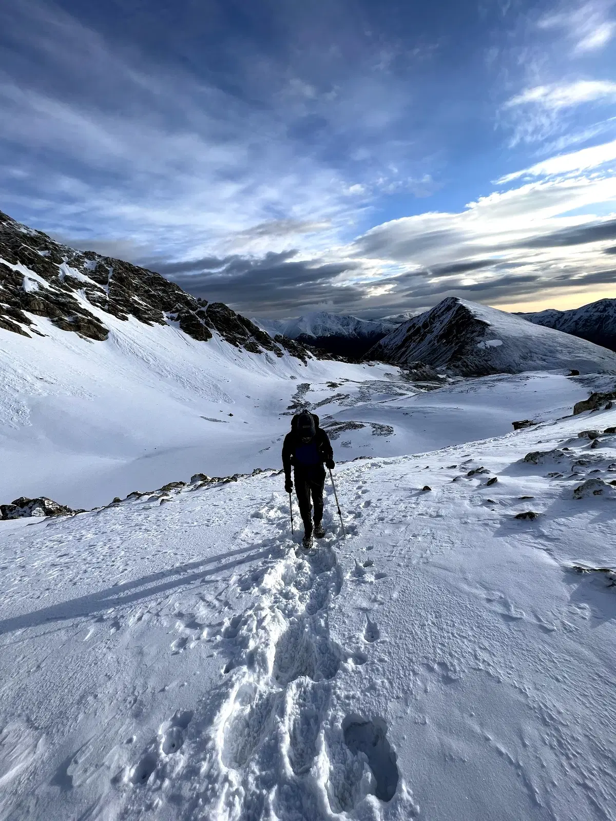 Dr. Spencer Hiebert hiking up a snowy mountain with trekking poles