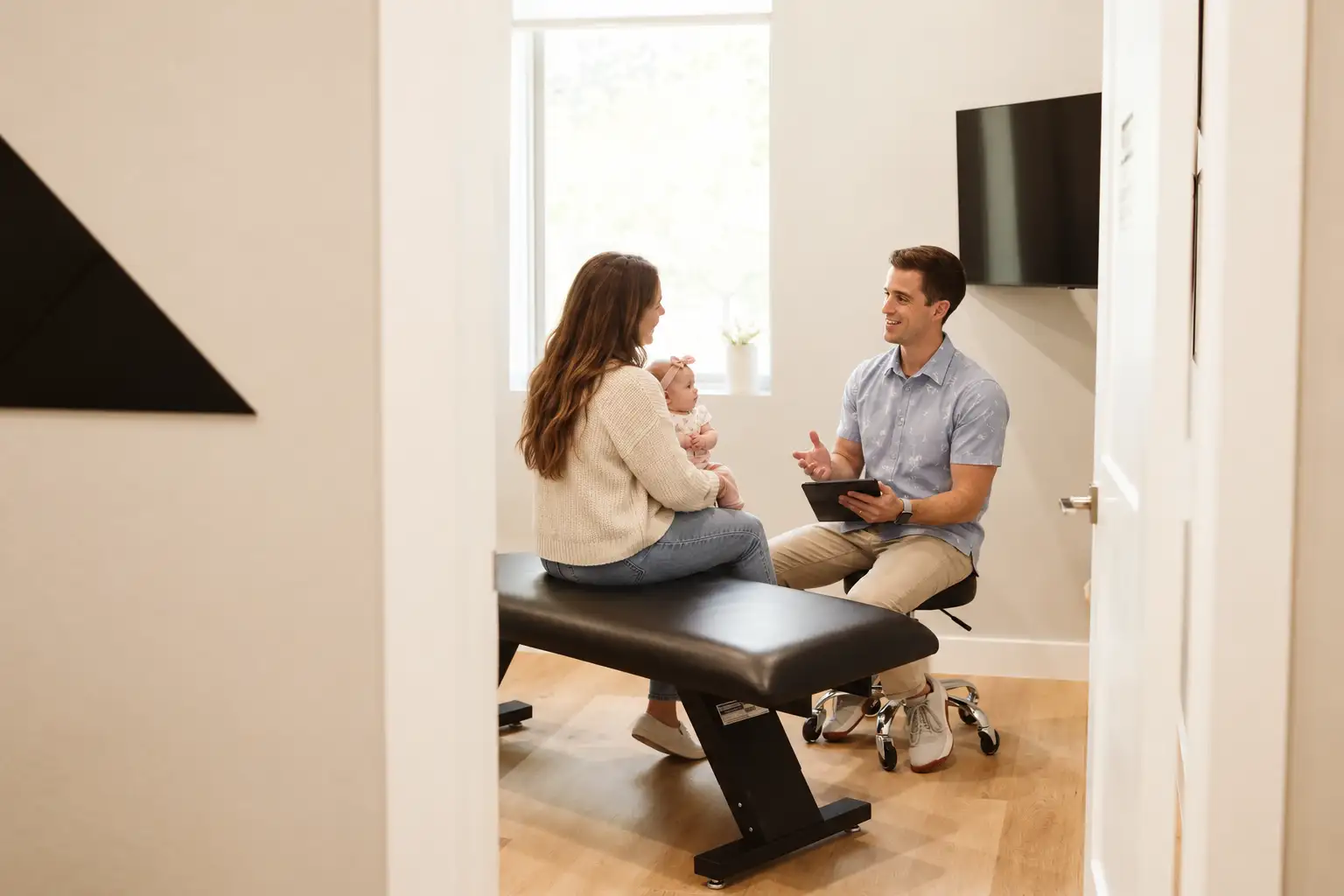Mother and baby speaking with a chiropractor in the clinic
