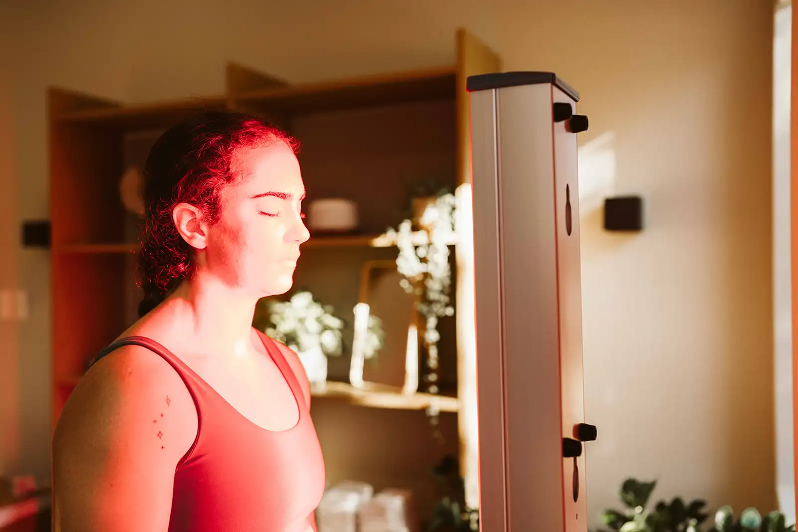 A woman facing a red light therapy panel