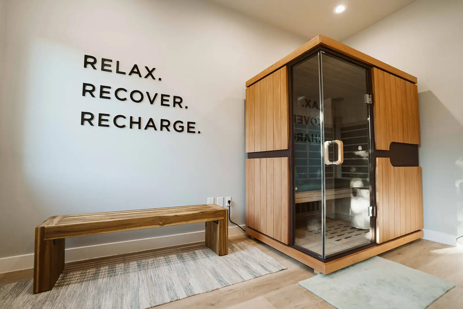 Sunlighten sauna and wooden bench in Summit’s recovery room