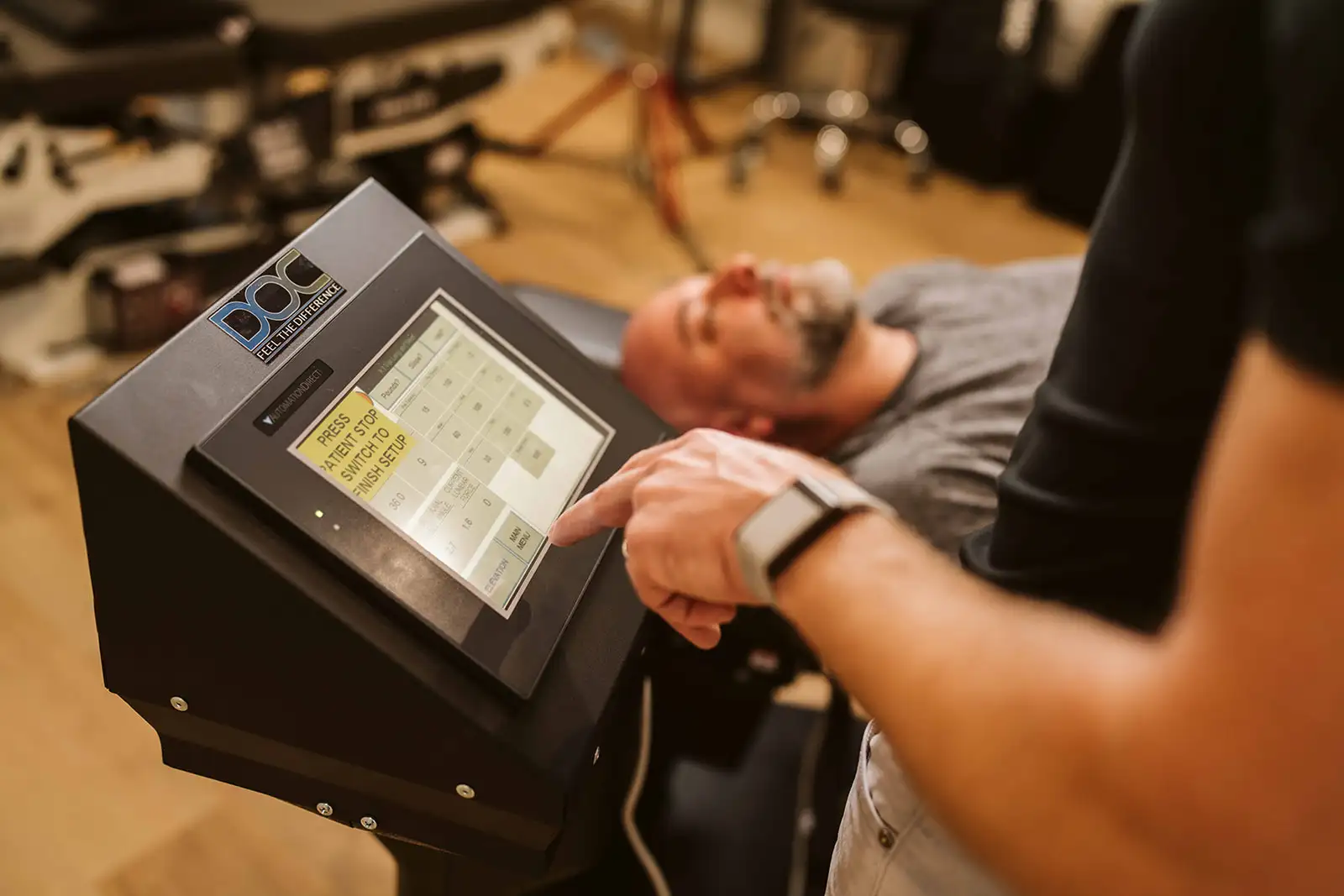 Dr. Hiebert adjusting the decompression table controls with a patient resting on the table