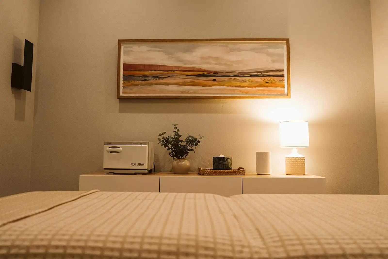 Massage table with a towel warmer, lamp and landscape artwork